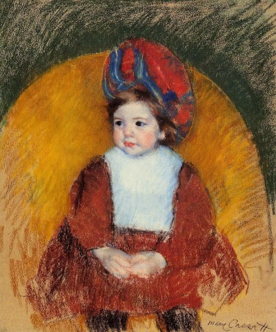 Margot en traje rojo oscuro sentada en la silla con respaldo redondo.