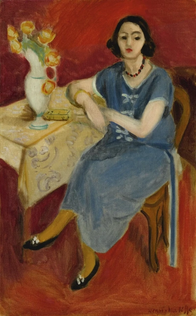 Mujer en azul en la mesa sobre un fondo rojo